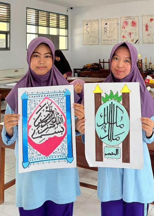 Dua santriwati Putri IMMIM Kelas IX menunjukkan hasil karya seni khatnya. (foto: ist/*)