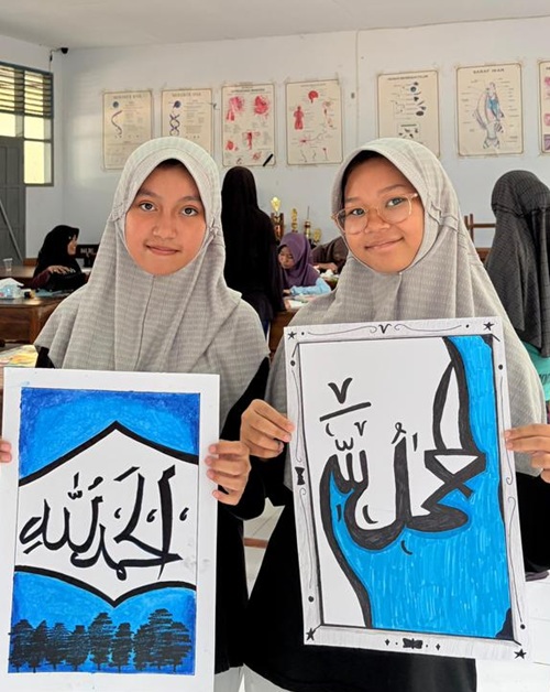 Dua santriwati Putri IMMIM Kelas IX menunjukkan hasil karya seni khatnya. (foto: ist/*)